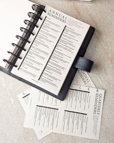 a black and white spiral notebook sitting on top of a table next to some papers