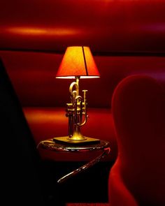 a trumpet lamp sitting on top of a table next to a red chair and wall