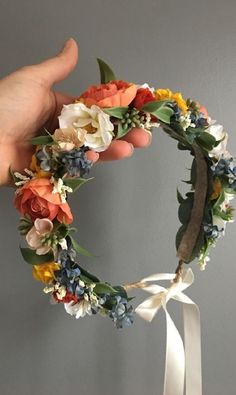 a hand holding a wreath with flowers on it