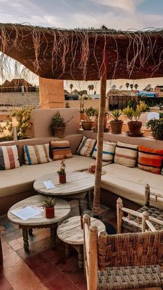 an outdoor seating area with wicker furniture and large potted plants on the roof