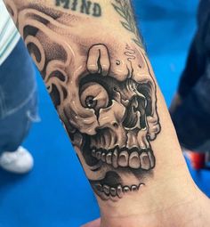 a person with a tattoo on their arm that has a skull in the middle of it