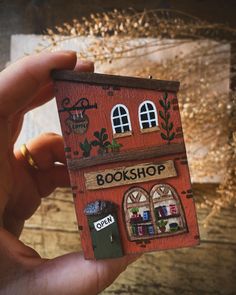 a hand holding up a miniature book shop