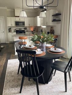 a dining room table with four chairs and a potted plant on top of it