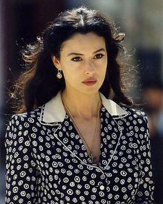 a woman in a black and white shirt is walking down the street