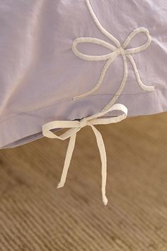 a white pillow tied to the back of a bed with a bow on it's side