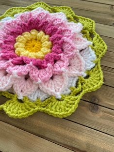 a crocheted flower sitting on top of a wooden table