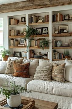 a living room filled with lots of white furniture and bookshelves on the wall