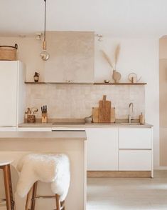 a white kitchen with two stools in front of the counter