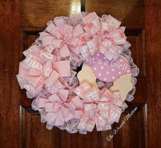 a pink and white wreath with words on it that say it's a girl