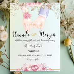 wedding card with two hands holding each other and flowers on the table next to it