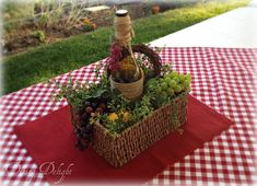 a picnic table with a basket filled with grapes and wine bottles on top of it