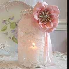 a pink flower sitting on top of a table next to a candle