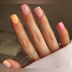 a woman's hand with pink and yellow nail polish