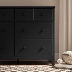 a black dresser sitting on top of a rug next to a white vase and ball