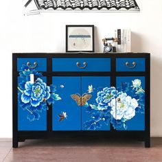 a blue and black cabinet with flowers painted on it