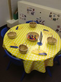 a table with yellow and white polka dot cloth, blue chairs and baskets on it