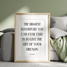 a framed poster sitting on top of a white couch next to pillows and a blanket