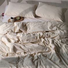 an unmade bed with two pillows and some food on the pillow case next to it