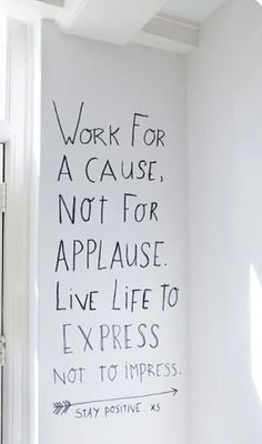 a white room with a black and white quote painted on the wall next to a window