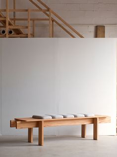 a wooden bench sitting in front of a white wall with four bowls on top of it