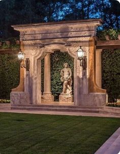 an outdoor area with a statue and lights in the background at night, surrounded by greenery