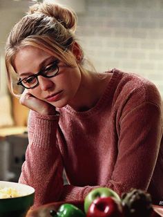 a woman sitting at a table in front of a bowl of food with her hand on her chin