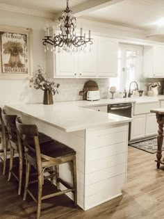 a kitchen with white cabinets and an island in the middle, surrounded by wooden chairs