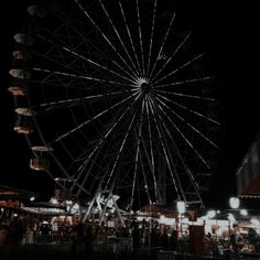 a large ferris wheel sitting next to a tall building on top of a dark sky