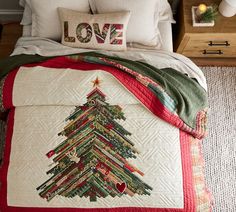 a quilted christmas tree on a bed with love written on the pillow and pillows