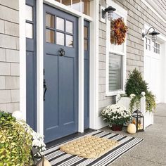 the front door of a house with blue doors and striped rugs on the porch