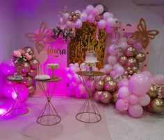 a pink and gold birthday party with balloons, cake and dessert table set up on the floor