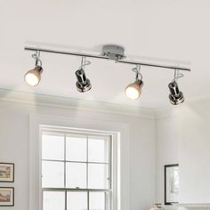 three lights are hanging from the ceiling above a bed in a room with white walls