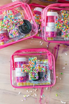 three pink bags filled with confetti and sprinkles on top of a wooden table