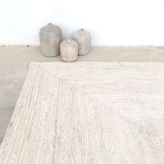 two vases sitting on top of a rug in front of a white wall and floor