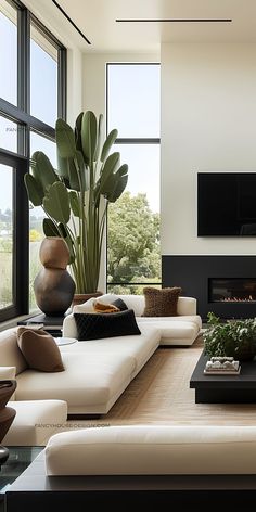 a modern living room with large windows and a fireplace in the center, surrounded by white couches