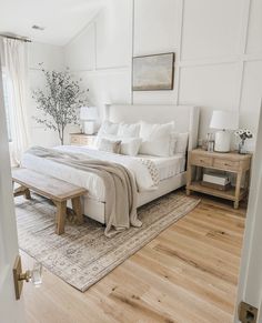 a bedroom with white walls and wood flooring has a large bed in the center