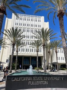 the california state university building is surrounded by palm trees and water fountain in front of it