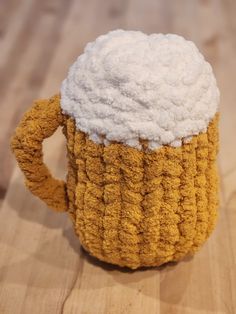 a close up of a knitted coffee cup on a wooden surface