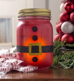 a red mason jar with a santa clause painted on it and christmas decorations in the background