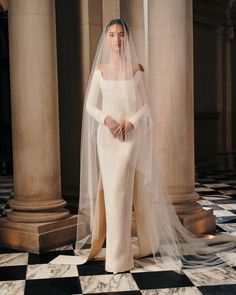 a woman in a white wedding dress and veil standing on a checkerboard floor