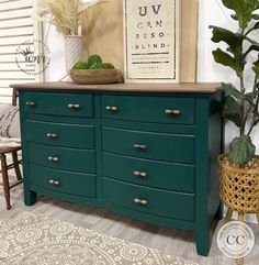 a green dresser sitting next to a potted plant