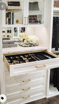 an open drawer in a white closet filled with jewelry and other personal items on display