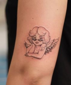 a small tattoo on the arm of a girl with angel wings and an eye patch