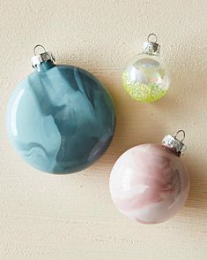 three ornaments are sitting on the floor next to each other, including one pink ornament