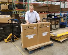 a man standing next to two boxes in a warehouse