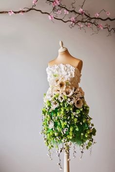 a dress made out of flowers and greenery is displayed on a mannequin