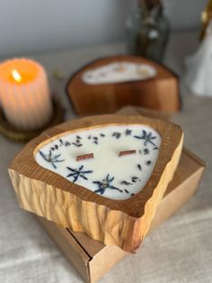 two candles sitting on top of a table next to a box filled with white frosting