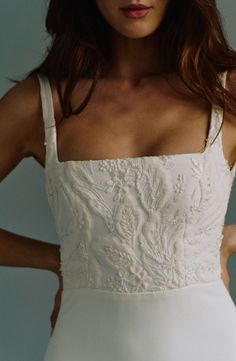 a woman in a white dress posing with her hands on her hips