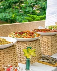 a table topped with plates of food next to a vase filled with flowers