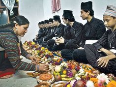 a group of people sitting on the ground with food in front of them and wearing hats